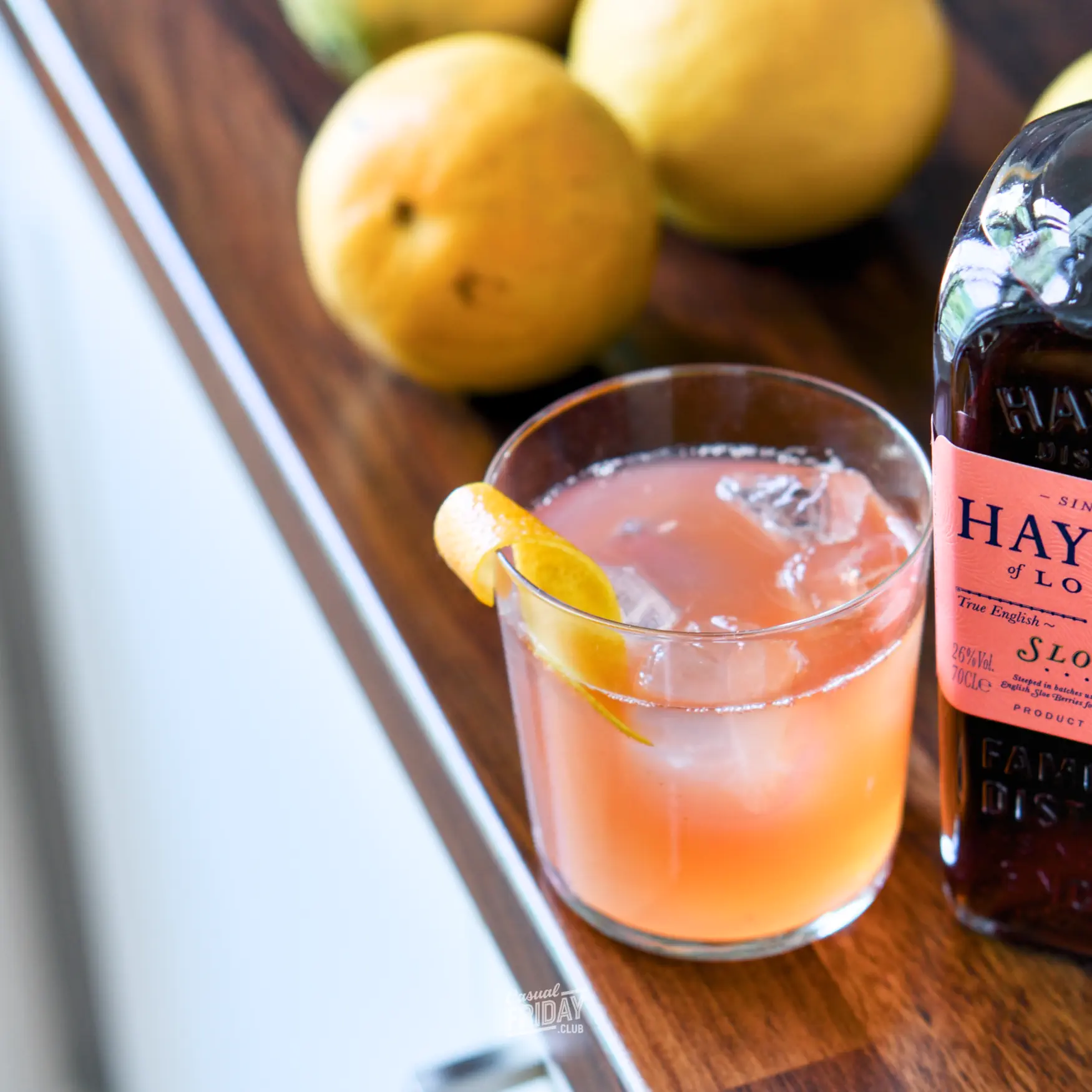 Sloe Gin and Bitter Lemon in a simple glass served with a lemon zest on a kitchen counter